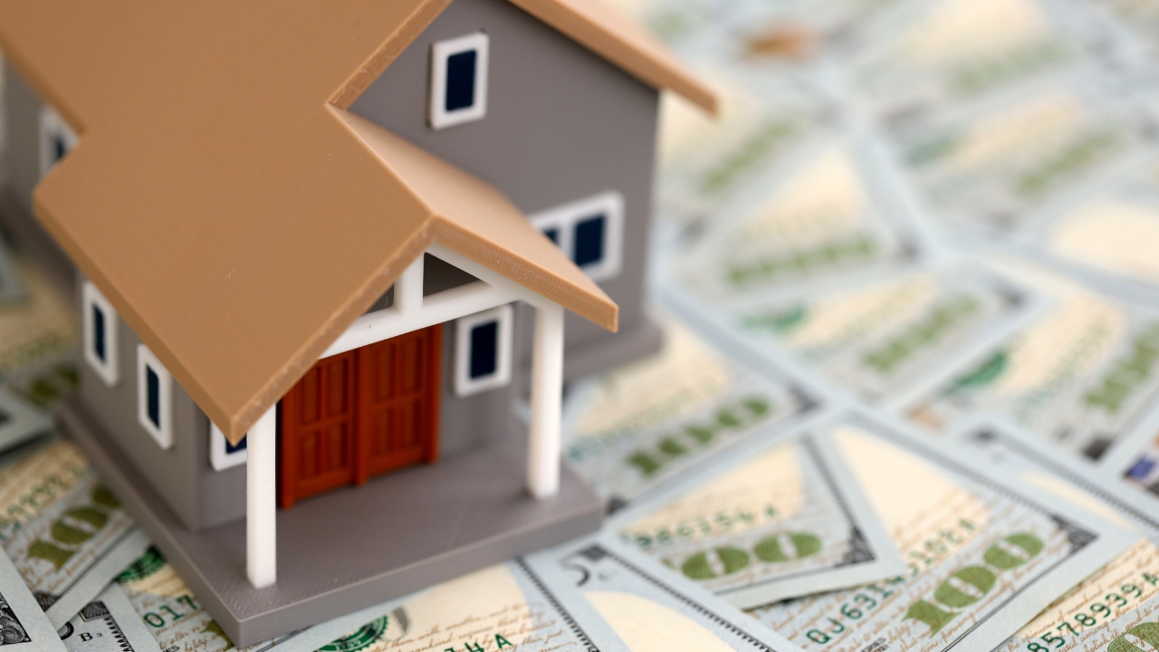 Small model house placed on top of US dollar bills