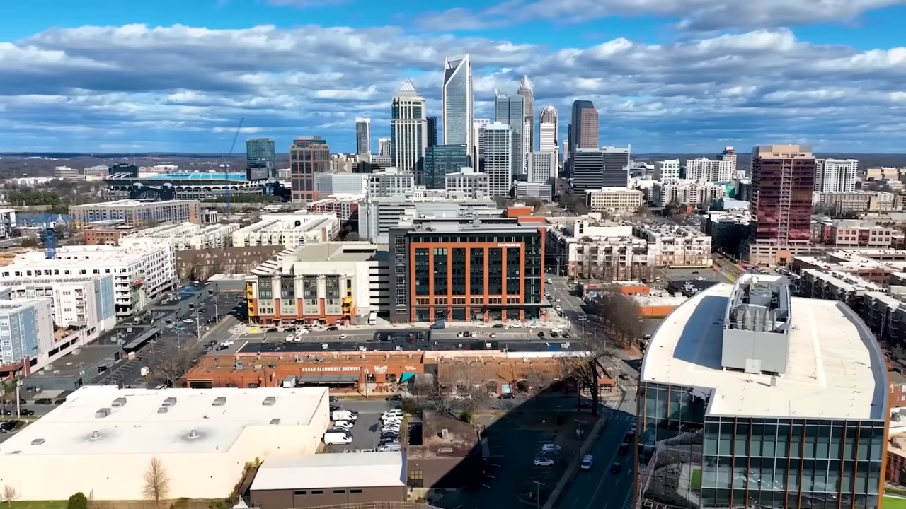 Charlotte skyline with modern buildings and mixed residential developments under a partly cloudy sky