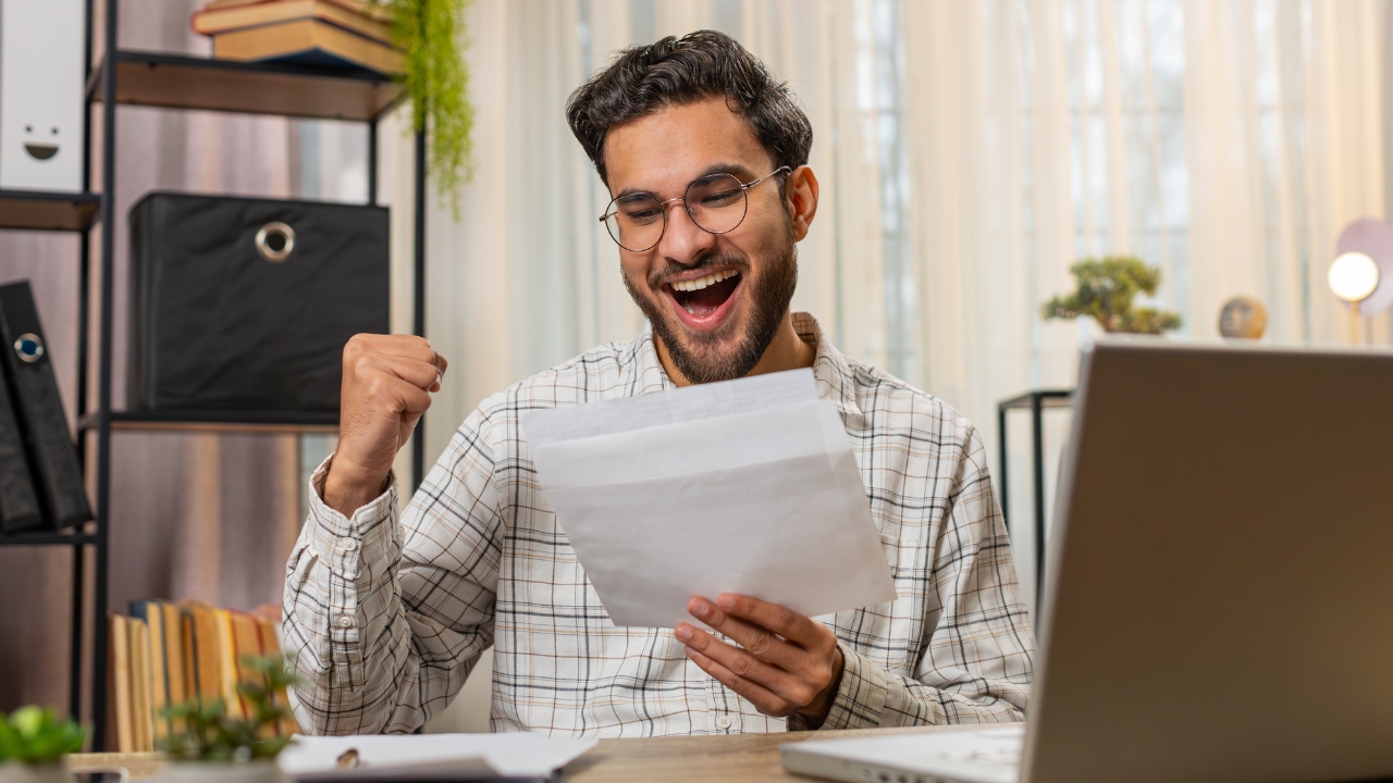 Man smiling at a document showing a good salary or income result