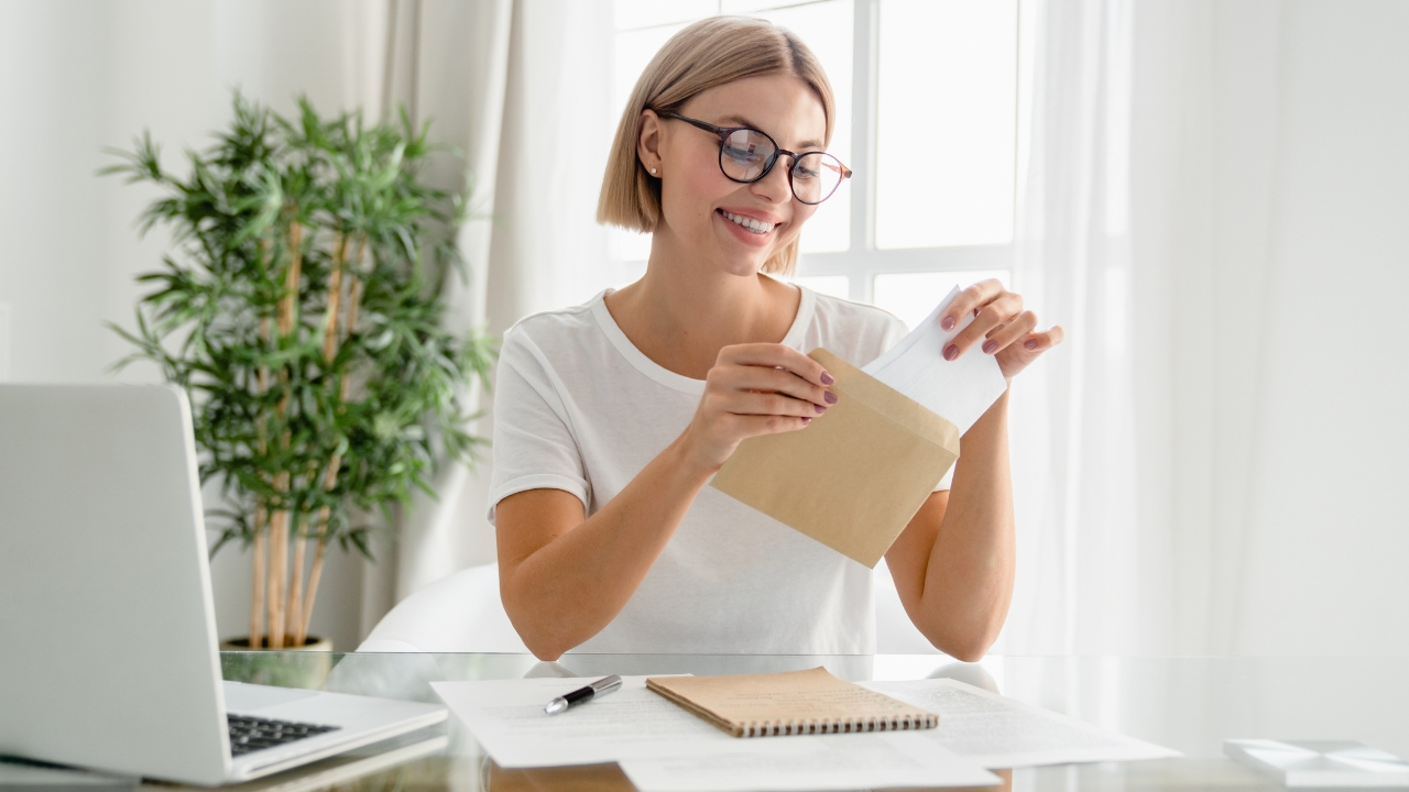 Woman opening a letter at her desk showing income or salary information