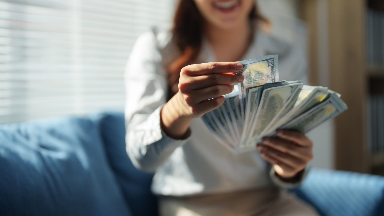 A woman counts cash at home while reviewing her salary needs for a future purchase