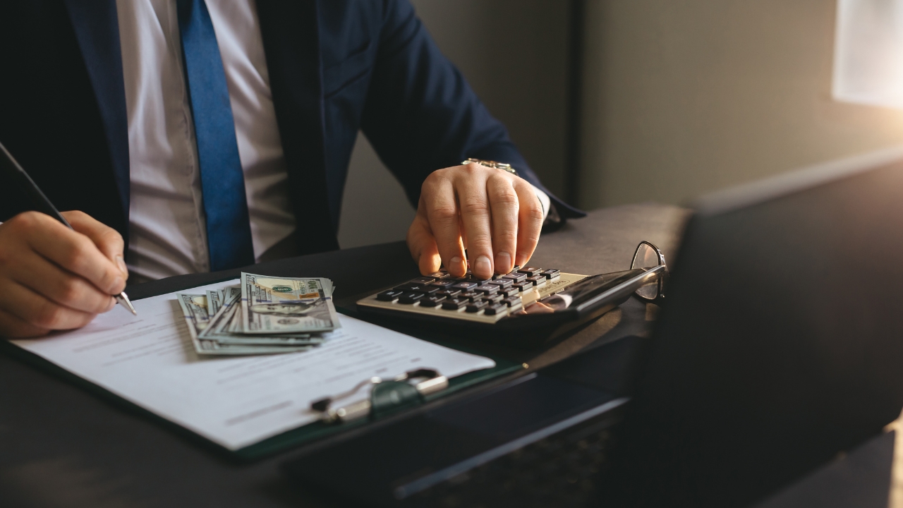 A mortgage professional calculates income needs beside loan documents and cash