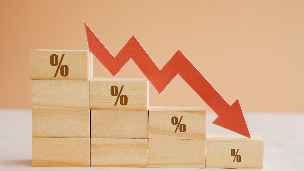 Wooden blocks with percent signs and a red arrow show falling mortgage rates
