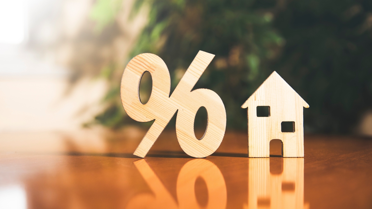 Wooden percent sign and small house show higher mortgage payment pressure